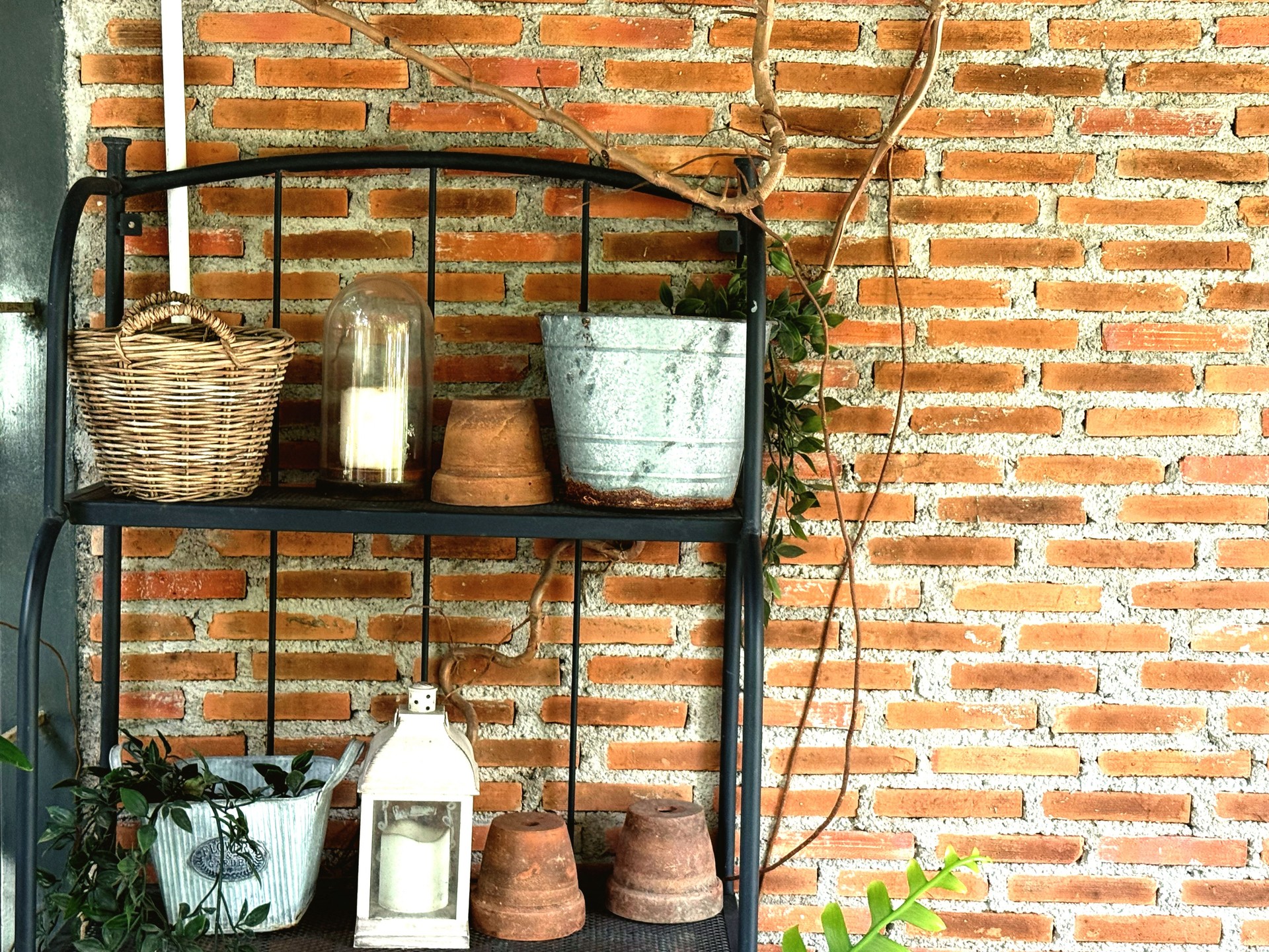 Vintage lamp and flower pot on the black shelf with brick wall background